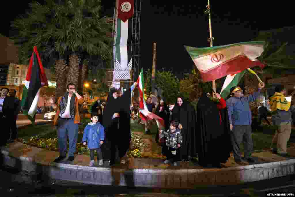 Demonstranții flutură steaguri iraniene și palestiniene în timp ce se adună în Piața Palestinei din Teheran în dimineața pe 14 aprilie. Armata israeliană a declarat că peste 100 de drone au fost lansate din Iran, surse de securitate din Irak și Iordania raportând au văzut&nbsp; zeci de drone zburând deasupra capului, iar oficialii americani au spus că armata americană le-a doborât pe unele.