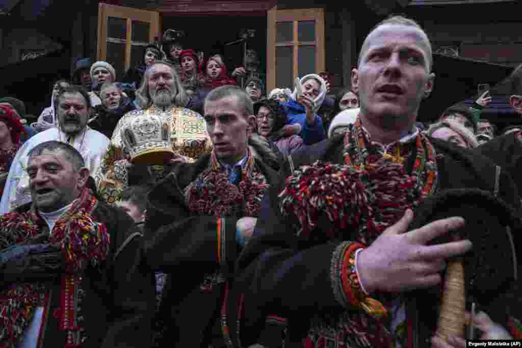 Мужчины поют колядные песни перед церковью. В этом году многие украинцы впервые отпраздновали Рождество 25 декабря, а не 7 января, когда этот праздник отмечает Россия. Изменение законодательно закрепили в июле. В законе, подписанном президентом Владимиром Зеленским, отмечается, что украинцы хотят «жить в соответствии со своими традициями». Там же говорится, что дата позволит им «отказаться от российского наследия навязывания Рождества» 