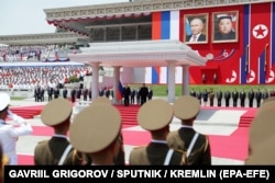 Portretele liderilor Rusiei și Coreei de Nord (deasupra personajelor reale) la ceremonia de primire a lui Putin, la Phenian, pe 19 iunie.