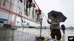 O femeie așază flori la gardul de lângă Crocus City Hall, situat la marginea vestică a Moscovei, Rusia, sâmbătă, 23 martie 2024.
