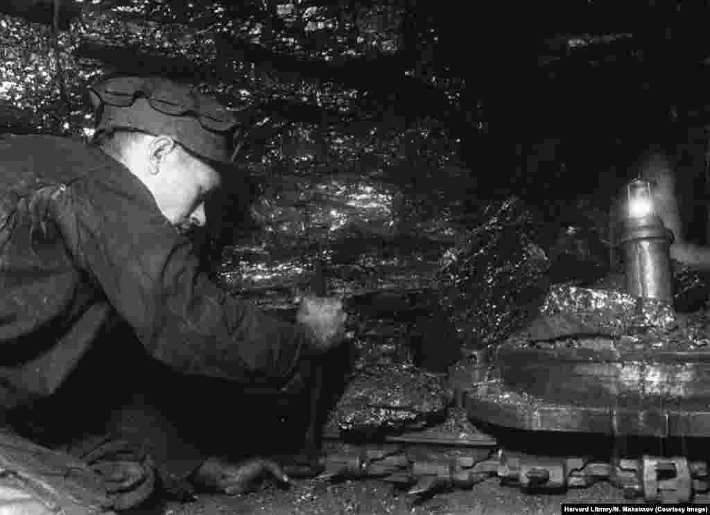 Un miner repară o mașinărie, într-o fotografie din seria intitulată de fotograf: „Reluarea mineritului de cărbune în Donbas”.