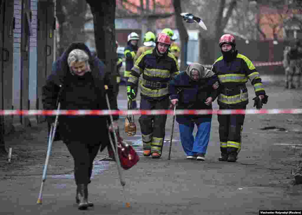 Salvatorii ajută localnicii să-și părăsească locuințele după atacul cu rachete.