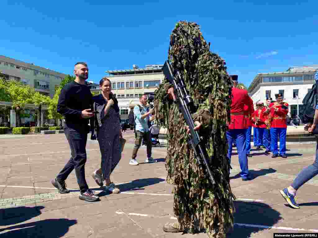 Vojnik u opremi za kamuflažu, dok su u pozadini pripadnici vojnog orkestra