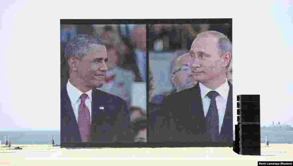 Veliki video ekran prikazuje tadašnjeg predsjednika Sjedinjenih Američkih Država Baracka Obamu i ruskog predsjednika Vladimira Putina pri dolasku na obilježavanje Dana D 2014. Govor predsjednika Obame naglasio je važnost NATO-a i kolektivne sigurnosti u svjetlu rastućih napetosti s Rusijom oko Ukrajine. &nbsp;