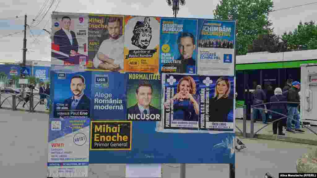 Afișe electorale în Piața Unirii din București, vizavi de o stație de tramvai. Oamenii trec grăbiți pe lângă chipurile zâmbitoare din afișe și nu se opresc nici măcar o secundă pentru a afla ce ofertă electorală au candidații pentru bucureșteni. 