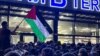Натовп під терміналом аеропорту у Махачкалі скандує антиізраїльські гасла. Учасник тримає прапор Палестини. Дагестан, 28 жовтня 2023 року