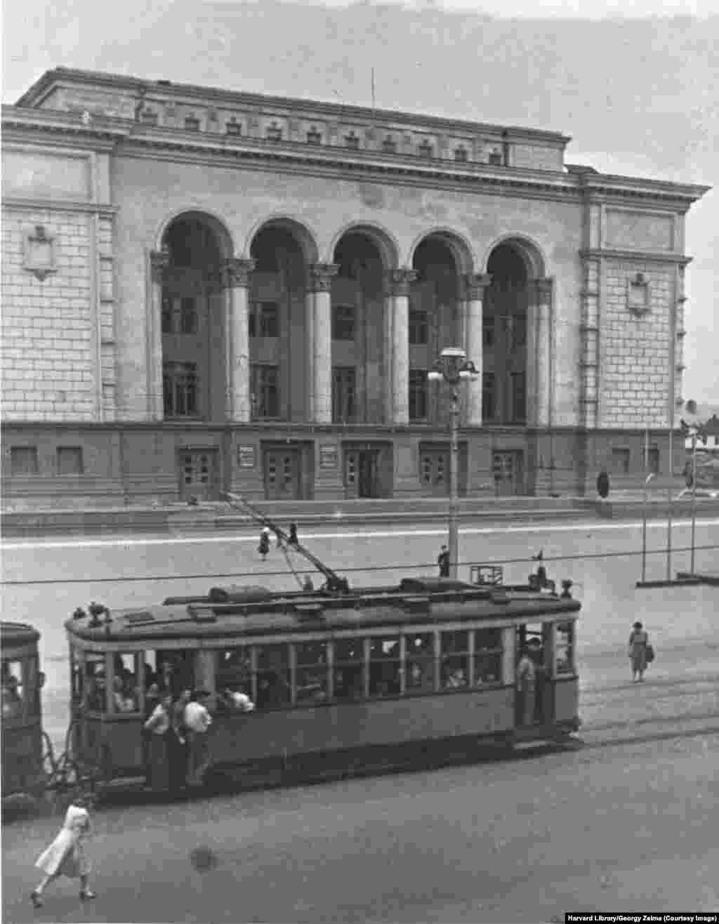 Un tramvai trece pe lângă Teatrul Donețk, cunoscut la acea vreme ca Teatrul Dramatic Stalino. Teatrul a primit atenție internațională în 2014 pentru că și-a continuat activitatea pe fundalul tulburărilor provocate de anexarea Crimeii și destabilizarea crescândă a Donbasului. 