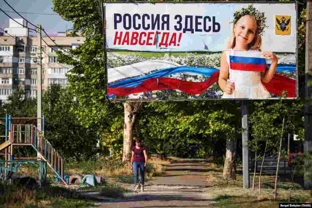 15 iulie 2022, Herson: O femeie trece pe lângă un afiș cu mesajul "Rusia este aici pentru totdeauna!"