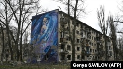 Мурал із зображенням жінки з дитиною на стіні сильно пошкодженого внаслідок обстрілів армією РФ житлового будинку в прифронтовому місті Авдіївці на Донеччині, 4 квітня 2023 року