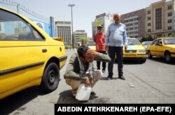 Un șofer de taxi din Teheran își umezește fața în timpul unei zile fierbinți în capitala iraniană