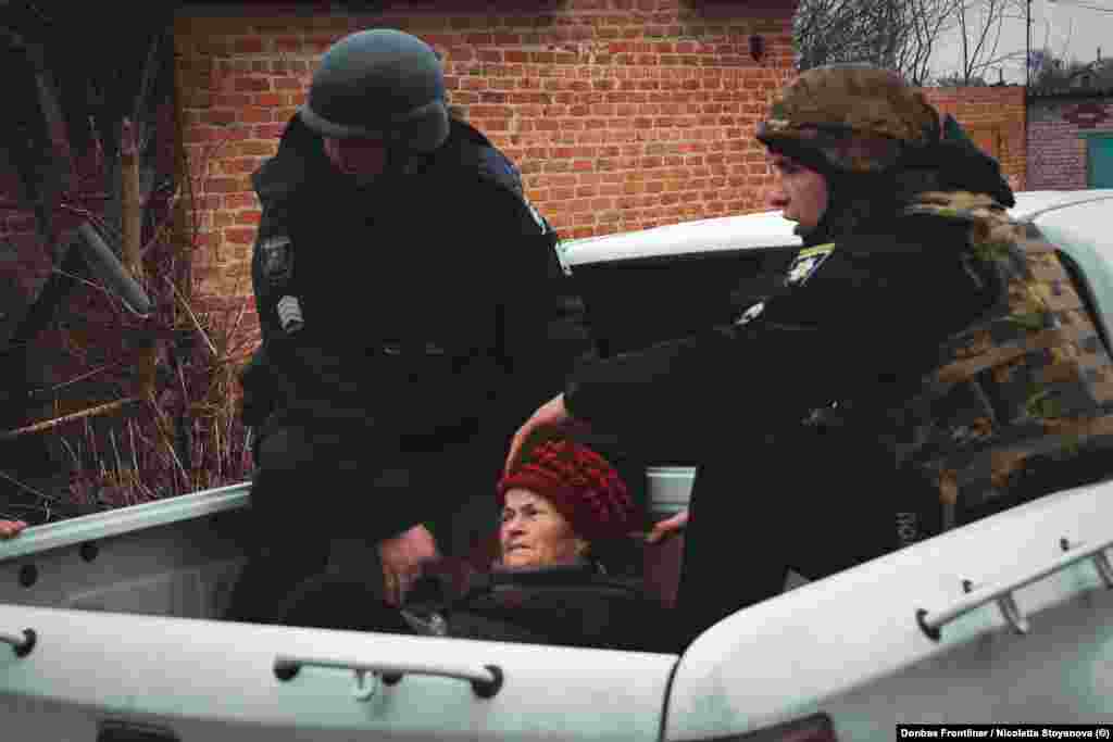 O femeie este ajutată de militarii ucraineni, în timp ce își părăsește casa din Velika Pisarivka, pe 18 martie. Autoritățile se grăbesc să evacueze localnicii după întețirea bombardamentelor rusești. 