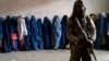 Taliban păzind femeile care așteaptă să primească rațiile alimentare distribuite de un grup de ajutor umanitar în Kabul, pe 23 mai.