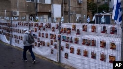 Një burrë duke kaluar pranë fotografive të pengjeve, kryesisht civilë izraelitë që u rrëmbyen gjatë sulmit të Hamasit më 7 tetor. Izrael, 22 nëntor 2023.