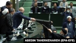 Președintele iranian Ebrahim Raisi (D) înmânează proiectul de buget președintelui parlamentului iranian Mohammad Bagher Ghalibaf, în timpul sesiunii parlamentare din 11 ianuarie 2023, Teheran
