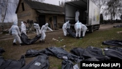 Волонтёры загружают тела мирных жителей, убитых в Буче, в грузовик перед тем, как перевезти их в морг. 12 апреля 2022 года
