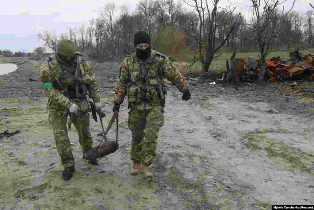 Ushtarët ukrainas mbajnë një predhë të pashpërthyer afër Motizhinit - një fshat në perëndim të Kievit, më 10 prill.