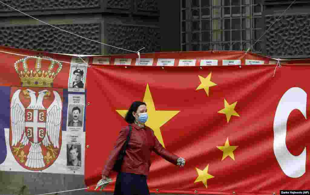 O femeie trece pe lângă afișe gigantice care leagă steagurile chineze și sârbe la Belgrad. Zoric spune că Rusia și China sunt „foarte prezente” în Serbia și semnalele de acest tip ar putea fi o modalitate de a sugera UE că țara are și alte opțiuni de aliniere geopolitică. 