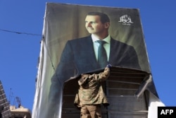 Alep, 30 noiembrie. Un militant rupe un portret al președintelui sirian Bashar al-Assad după ce jihadiștii și aliații lor au intrat în orașul din nordul Siriei