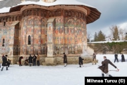 Tineri jucându-se în zăpadă din curtea Mănăstirii Moldovița, județul Suceava