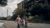 Doi localnici trec pe lângă o clădire distrusă de război în centrul orașului Izium din regiunea ucraineană Harkov, recent eliberată. 13 septembrie 2022.