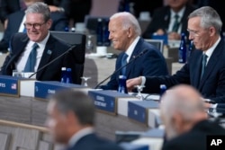 Președintele american Joe Biden își ia locul în sala de ședințe de la summitul NATO, între premierul britanic Keir Starmer și secretarul general Jens Stoltenberg.
