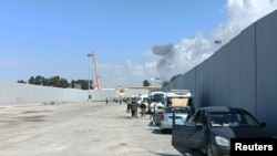 Vullnetarë egjiptianë duke shikuar tymin duke u ngritur nga ana palestineze në pikën kufitare Rafah, teksa grupet e ndihmave prisnin për rihapjen e kufirit, më 17 tetor 2023.