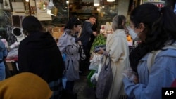 Femei iraniene protestând, aproape imperceptibil pentru un străin, în piață la Teheran, la 14 noiembrie 2022 - ele nu poartă hijab.