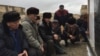 Мужчины слушают слова молитвы на кладбище на поминках по жертвам разгона демонстрации нефтяников в Жанаозене. Поселок Тенге,10 декабря 2016 года.