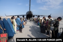 Personalul US Air Force ajută pasagerii să se îmbarce la bordul unui avion cargo militar în timpul evacuării din Afganistan din august 2021.