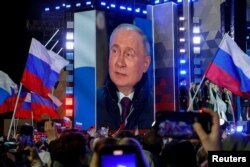 Președintele rus Vladimir Putin apare pe un ecran al scenei în timp ce participă la un miting care marchează cea de-a 10-a aniversare a anexării ilegale de către Rusia a Crimeei de la Ucraina, în Piața Roșie din centrul Moscovei pe 18 martie.