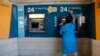 Уборщица стирает пыль с банкомата перед входом в отделение Bank of Cyprus в Никосии, 28 марта 2013