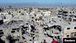 Palestinci gledaju na kuće uništene u izraelskim napadima tokom sukoba, usred privremenog primirja između Izraela i militantne grupe Hamas, u izbegličkom kampu Kan Iounis, u južnom pojasu Gaze, 29. novembra 2023.