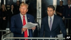 Fostul președinte american Donald Trump, vorbind jurnaliștilor, alături de avocatul său, în timp ce se prezintă la una din ședințele tribunalului din New York. 
