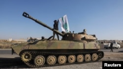 Un luptător rebel pe tanc, cu un steag al grupării HRT, la Saraqeb.