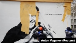 Muncitorii acoperă cu vopsea o creație în graffiti cu chipul lui Alexei Navalnîi. La un an de la întemnițarea sa, opozantul cel mai aprig al lui Vladimir Putin spune că nu știe dacă va mai ieși vreodată din închisoare.