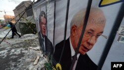 Un afiș în Kiev cu inscripția Vine Sărbătoarea!... și care îi reprezintă pe Azarov și Ianukovici după gratii, 28 ianuarie, 2014