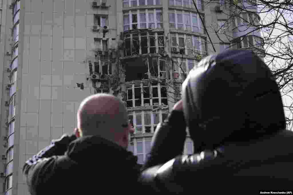 Localnicii în fața unui bloc avariat de o dronă doborâtă în timpul unui atac de noapte în Kiev.