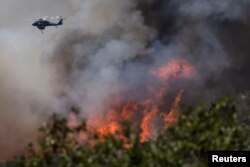 Vatrogasni helikopter izbacuje vodu na padini pored Mariposa u Kaliforniji, 24. juli 2022.