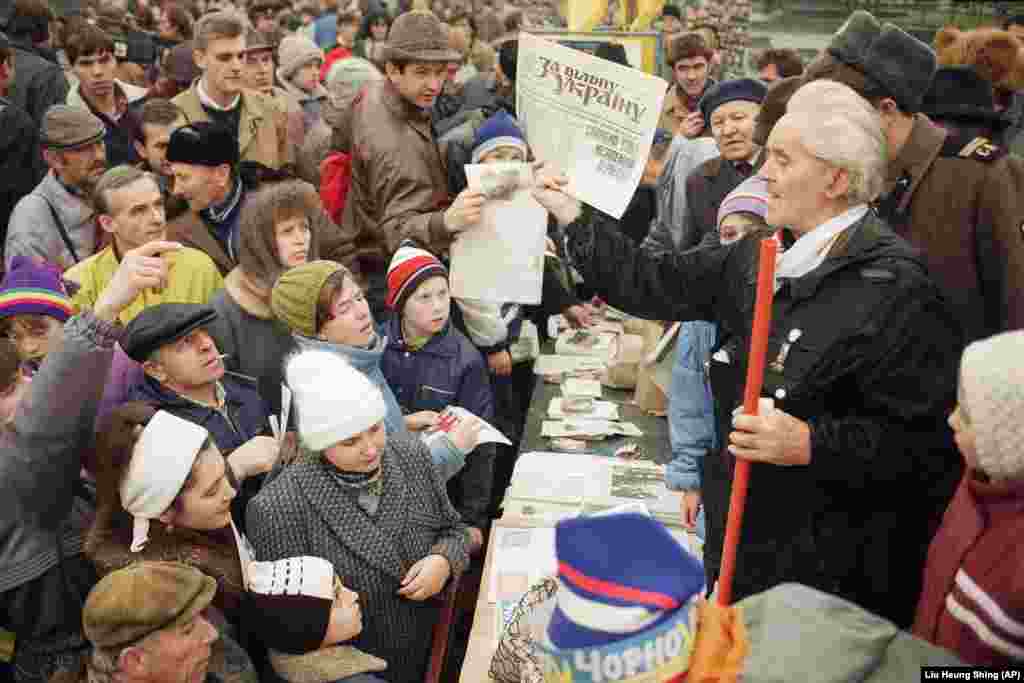 A campaign worker holds up a newspaper that says "For a Free Ukraine" in Kyiv. 