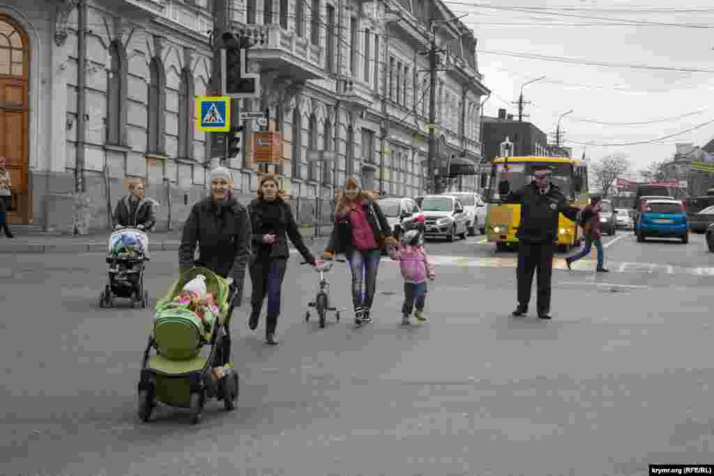 Светофорлар істемегендіктен жаяу жүргіншілер көшеден реттеуші көмегімен өтеді. 