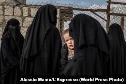 O rusoaică își poartă copilul în timp ce așteaptă la coadă la un spital improvizat dintr-o tabără din nordul Siriei care găzduiește familiile bărbaților care au luptat pentru SI