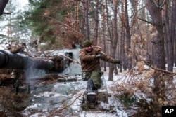 Un soldat cu dizabilități din Brigada 127 din Ucraina, care și-a pierdut un picior în luptă în 2015, își scoate camuflajul de pe obuzierul autopropulsat. 10 februarie 2025.