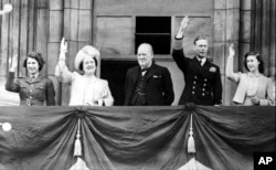 De la stânga la dreapta: Prințesa Elizabeta (viitoarea Regină), mama ei, Regina Mamă, premierul Marii Britanii, Winston Churchill, Regele George al VI-lea și Prințesa Margareta, salutând mulțimea adunată în fața Palatului Buckingham cu ocazia încheierii celui de-al Doilea Război Mondial, 8 mai 1945.