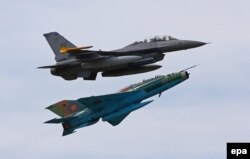 Avionul F16 al Forțelor Aeriene SUA (sus) și un MIG 21 Lancer, aparținând Forțelor Aeriene Române (jos), efectuează o manevră de zbor strânsă în timpul exercițiului militar comun româno-american.