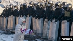 O femeie îngenunchează în fața trupelor forțelor speciale ale poliției. Kiev, 24 ianuarie 2014