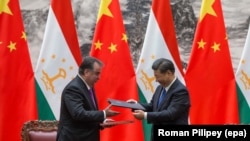 Președintele chinez, Xi Jinping, (dreapta) și președintele tadjik, Emomali Rahmon, fac schimb de documente în timpul unei ceremonii de semnare la Beijing, pe 31 august 2017.