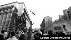 Dictatorul Nicolae Ceaușescu și soția sa, Elena Ceaușescu, părăsesc clădirea Comitetului Central al PCR, la ora 12.00 și câteva minute, pe 22 Decembrie 1989. Fug din fața sutelor de mii de protestatari. Reuters/Lucian Crișan.