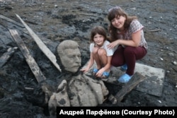 Supruga i kćerka fotografa Andreja Parfjonova poziraju ispred dijelova Staljinove statue.