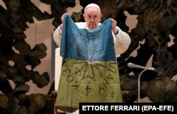 Papa Francisc ține un steag adus de la Bucea, în timpul audienței generale săptămânale. Vatican, 6 aprilie 2022.