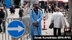 A man wearing a protective face mask waits to disinfect carts at a street market in the Georgian capital, Tbilisi.